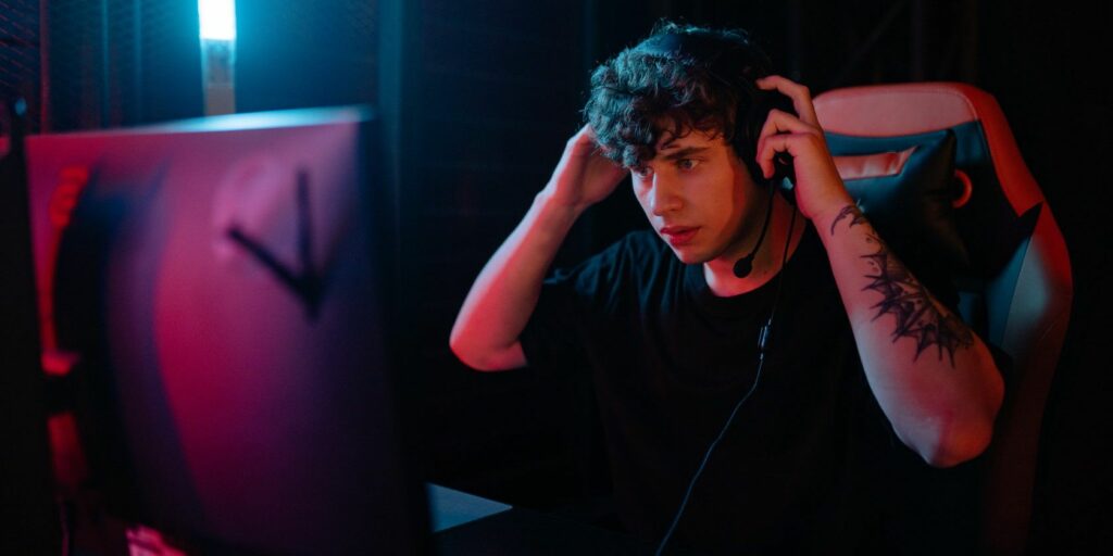 person sitting at desk wearing headphones playing online games