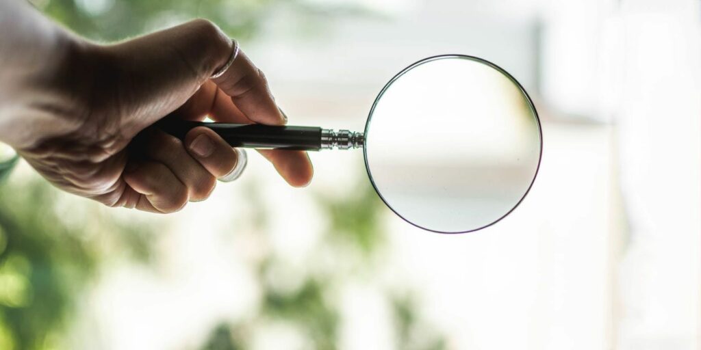 Image of a person holding magnifying glass to search for something