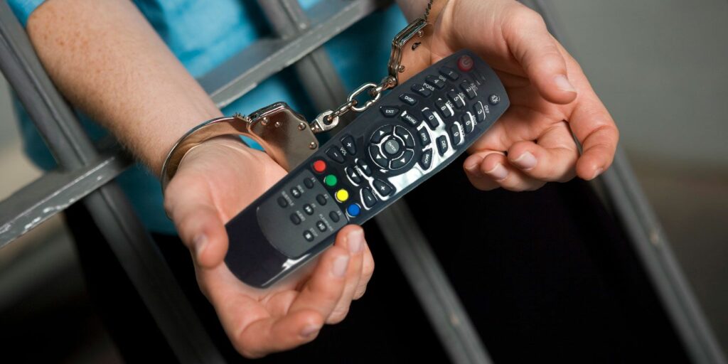 Man with handcuffs in jail holding remote