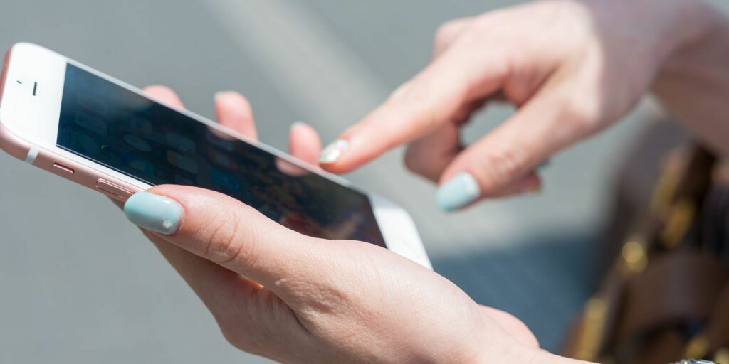 hands holding iPhone on its home screen