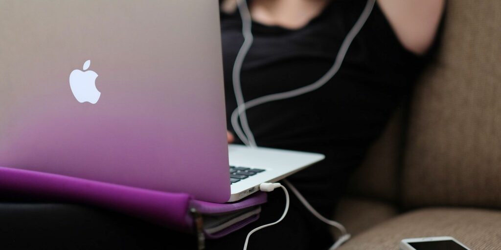 Person listening to music with headphones on a Mac