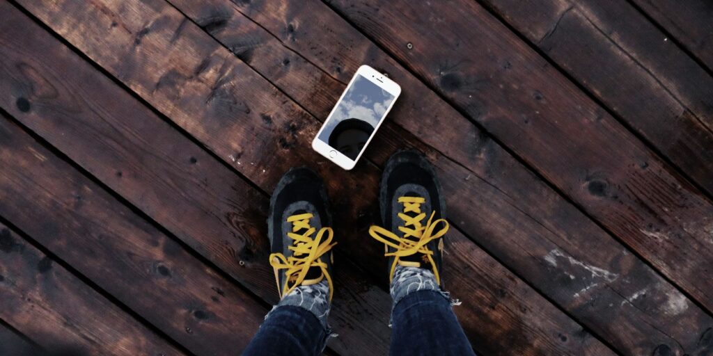 iPhone lying on the floor at someone's feet.