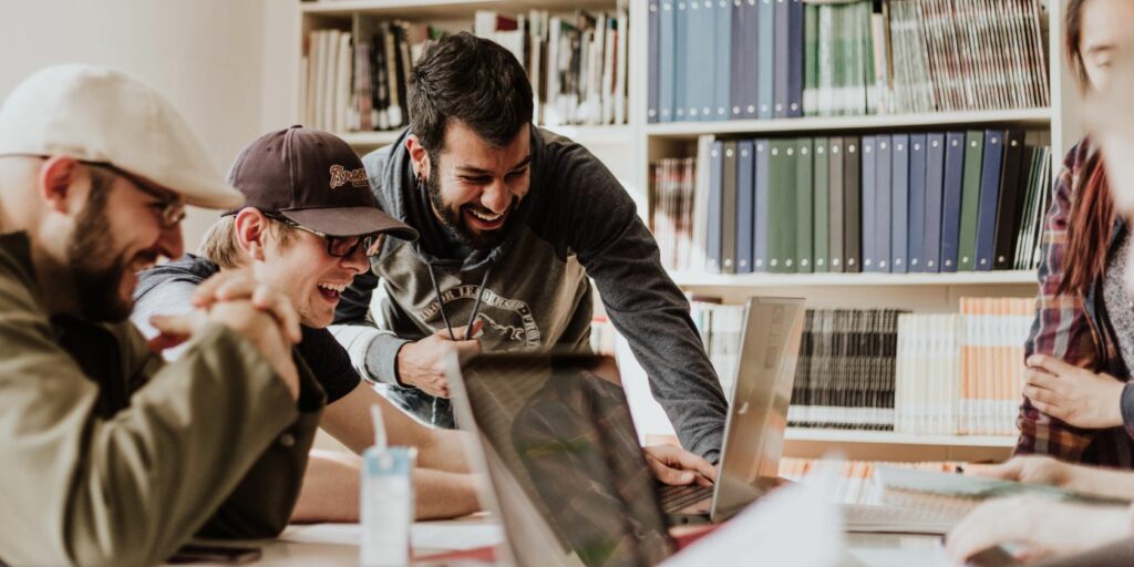 Image shows three men laughing at a computer screen