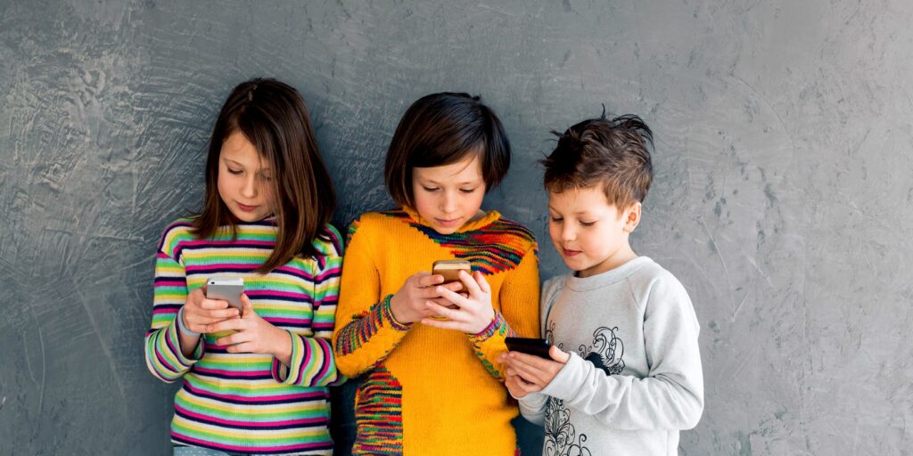 three young children using smartphones feature