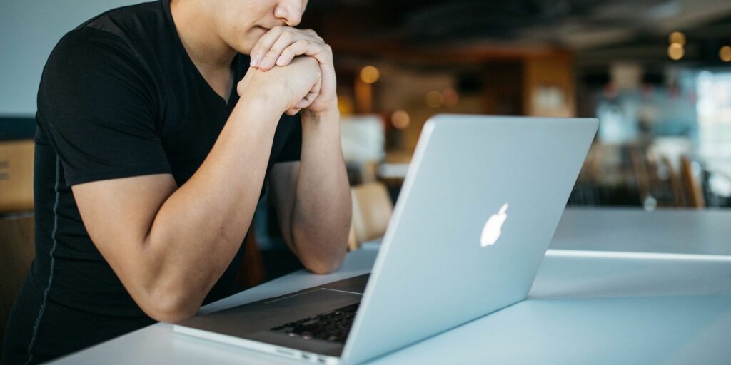 Man sat staring at a MacBook on a table