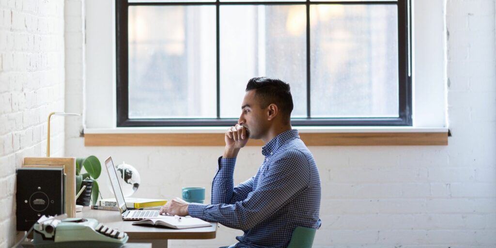 a man working on his laptop sitting by the window