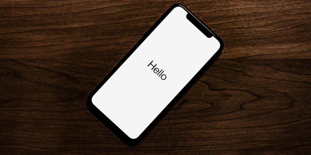 Image showing an iPhone on the Hello screen after a reset on a wood table